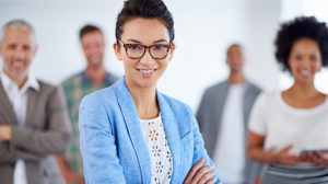 Photo of young woman in work attire with co-workers in background discussing how to attract and retain millennials