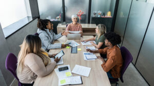 A photo of a woman and her team discussing navigating leadership in uncertainty.