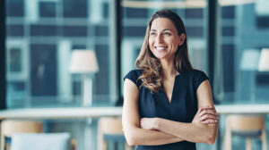 A smiling woman contemplates a learning agility workshop and learning agility training for the leaders at her organization