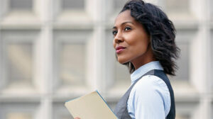 Portrait of young business woman holding paper work, looking away, side view, thinking about why leadership development is important and the best reasons to invest in leadership training